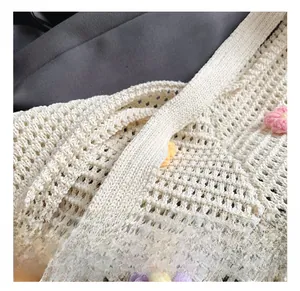 Détail de la large bandoulière et fleurs tricotées colorées sur le sac cabas en maille