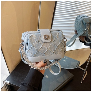 Detailed view of light blue denim pleated crossbody bag with silver clasp and metal chain