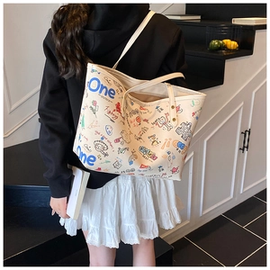 Détail du grand sac cabas beige avec imprimés graffiti colorés sur un modèle porté épaule