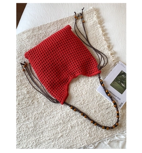 Détail d'un sac cabas en crochet rouge avec tissage évidé et bandoulière perlée