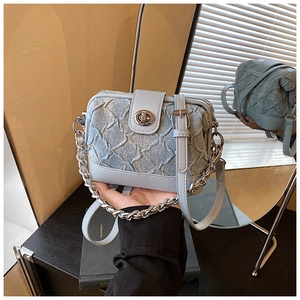 Detailed view of light blue denim pleated crossbody bag with silver clasp and chain handle