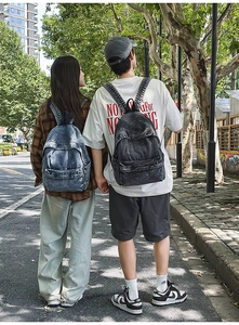Outdoor shot showing back view of light blue and dark grey vintage denim backpacks