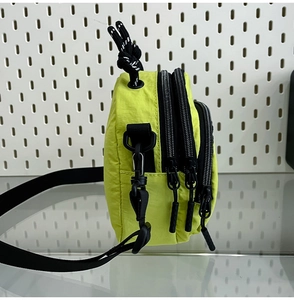 Vue détaillée du sac bandoulière en nylon fluorescent avec trois compartiments zippés