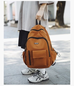 Outdoor street view of a trendy orange commuter backpack with multiple functional pockets