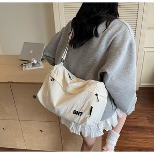 Detail view of cream white nylon crossbody bag with BNT logo and spacious design