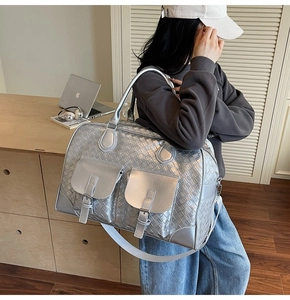 Close-up of silver woven texture travel bag with metal buckles and adjustable strap