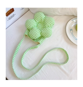Dettaglio della borsa a tracolla a fiori vichy verde su sfondo di tessuto bianco