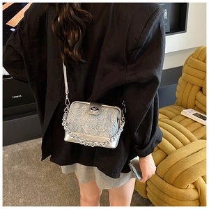 Detail of blue jacquard handbag with silver chain strap shown worn by a model