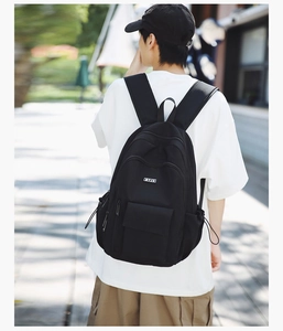 Rear view of a black high-density nylon backpack worn by a person in a street setting