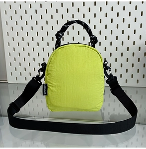 Vue détaillée du mini sac bandoulière en nylon jaune fluo imperméable sur verre