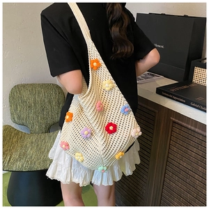 Gros plan d'un sac cabas en maille crème orné de fleurs colorées avec une large bandoulière