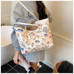 Detail view of a large tote bag with colorful graffiti prints and white shoulder straps