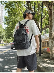 Close-up of vintage grey denim backpack showing front zipper pocket and fabric texture