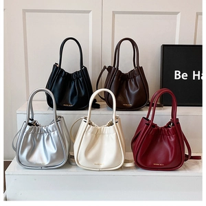 Detail of multi-color pleated bucket bags with gold branding and thin shoulder straps