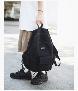 Detail of a black nylon backpack with multi-layer zippers and woven logo label