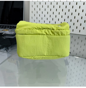 Détail du sac bandoulière en nylon vert fluo étanche avec fermeture sur un bureau