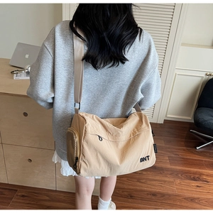 Detail view of khaki crossbody travel bag with BNT embroidery on durable nylon material