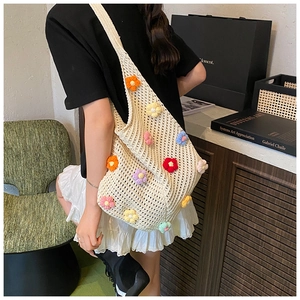 Détail d'un sac cabas en crochet blanc avec fleurs 3D tricotées porté par un mannequin