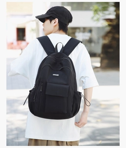 Rear view of black nylon backpack featuring flap pocket and drawstring side pockets