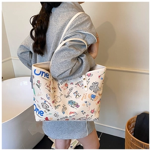 Detailed close-up of a white tote bag with colorful graffiti prints and shoulder straps