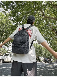 Close-up of retro gray washed denim backpack with wide straps and spacious zipper pocket