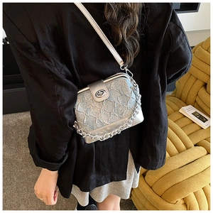 Close-up of pleated silver blue crossbody bag with chunky metal chain and turn-lock closure
