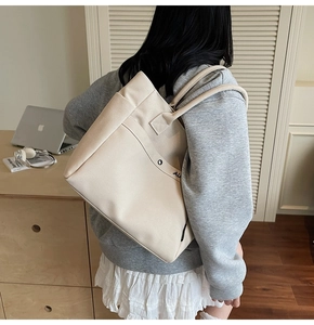 Detail of canvas tote bag showing side pocket and embroidery while worn by a model