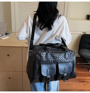 Detailed close-up of a black woven travel bag featuring front pockets and metal buckles