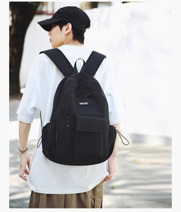 Detail of ergonomic shoulder straps and side drawstring pockets on a black travel backpack