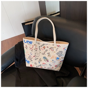 Détail de l'imprimé graffiti coloré sur un grand sac cabas en cuir synthétique crème