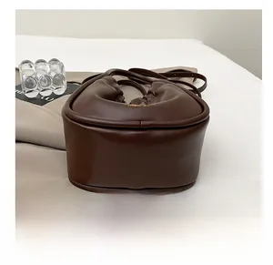 Detail showing the reinforced bottom and smooth brown leather texture of the bucket bag