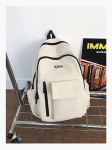 Detail view of cream-white nylon backpack with functional zip pockets and brand label