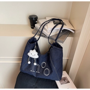 Close-up of denim tote bag with letter embroidery and white cloud plush charm
