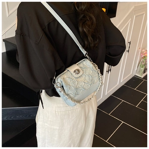 Detail view of light blue quilted denim crossbody bag with silver chain and metal clasp