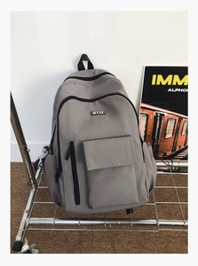 Close-up of a dark grey nylon travel backpack with multi-pocket design on a metal stand