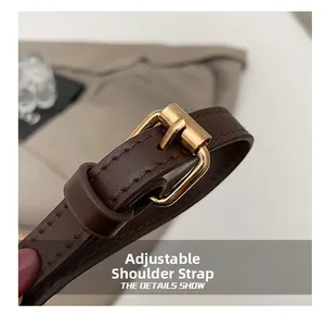 Detail of adjustable dark brown leather shoulder strap with golden buckle and fine stitching
