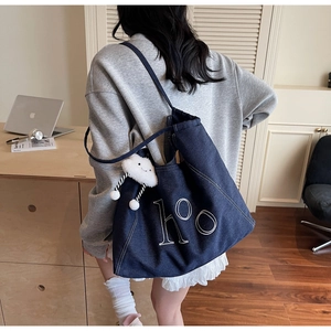 Close-up of dark blue denim tote bag with white ho embroidery and cloud plush charm