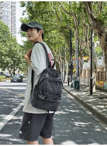 Street view of a man wearing a large vintage washed charcoal denim travel backpack