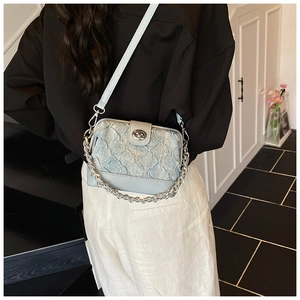 Detail of light blue quilted crossbody bag featuring silver chain and metal twist lock