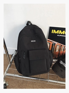 Detail view of a black canvas backpack with MYJC patch on a metal trolley