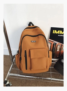 Detail view of mustard yellow backpack with multi-compartments on metal display rack
