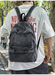 Detail of dark grey marble wash denim backpack showing spacious structure and padded straps