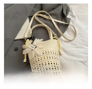 Détail de sac seau beige avec motif ajouré et grand pendentif fleur blanche en tulle