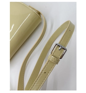 Gros plan sur la bandoulière en cuir verni jaune crème avec boucle argentée détaillée