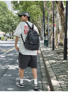 Detailed outdoor shot of a vintage charcoal washed denim backpack with metal zippers