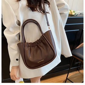 Detail of dark brown pleated bucket bag with gold lettering and adjustable shoulder strap