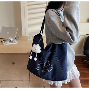 Detail of blue denim tote bag with white hs logo print and cloud charm accessory