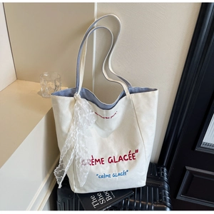 Close-up of cream canvas tote bag with blue striped lining and lace scarf detail