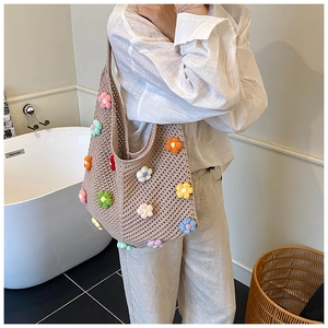 Détail du sac cabas au crochet fait main avec des fleurs 3D colorées sur fond beige