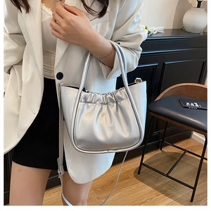 Chic silver pleated bucket bag with metallic finish shown held by a model in a modern room